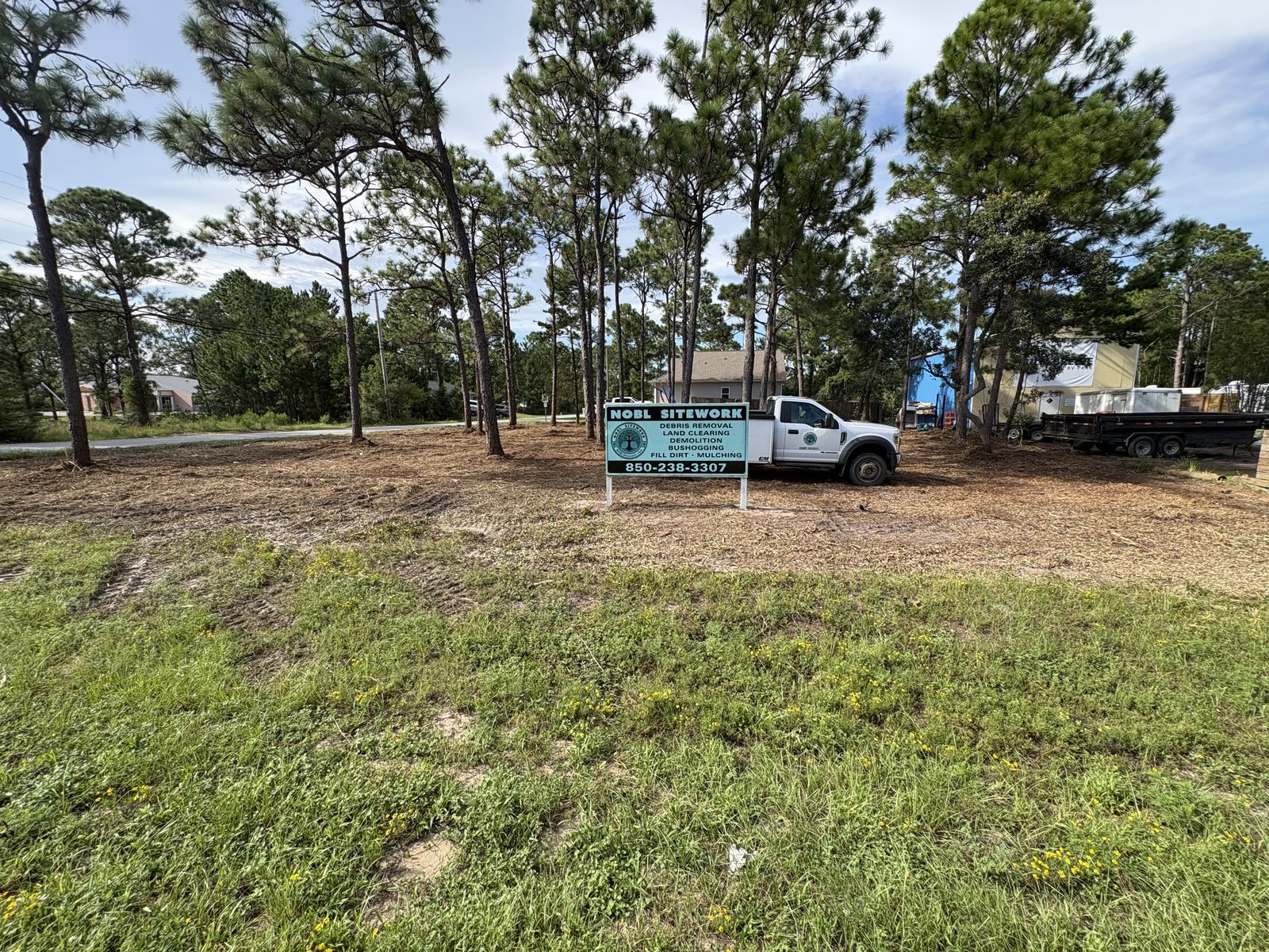 Finished mulched lot seen from the road with the NOBL Sitework sign and truck